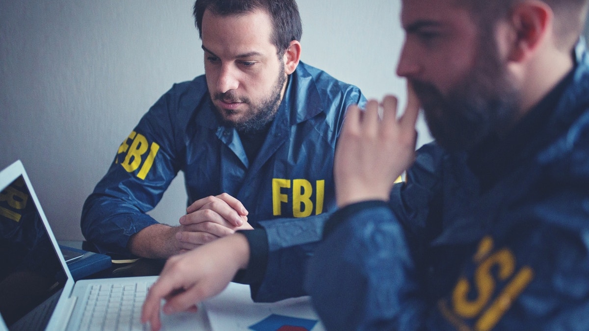 FBI agents sitting in front of a computer.