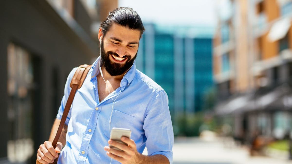 smiling man in blue shirt with smartphone