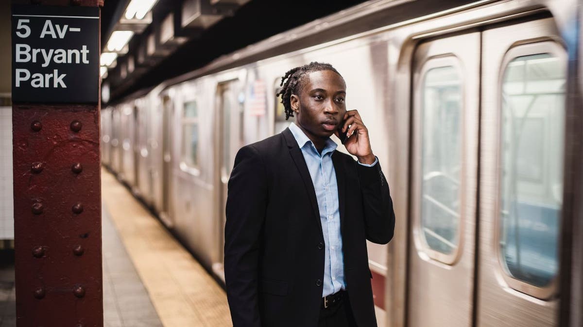 Man talks on his phone while at a subway station