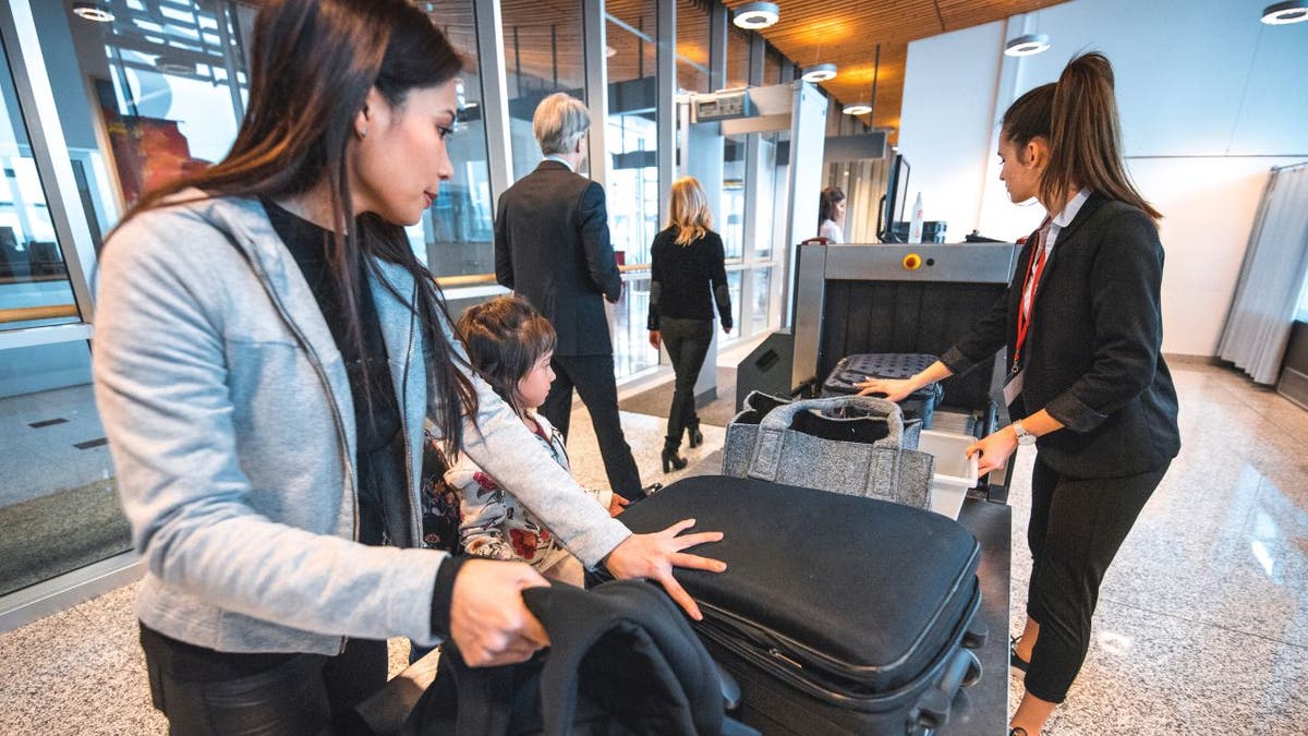 People passing their bags through the machine at the airport.