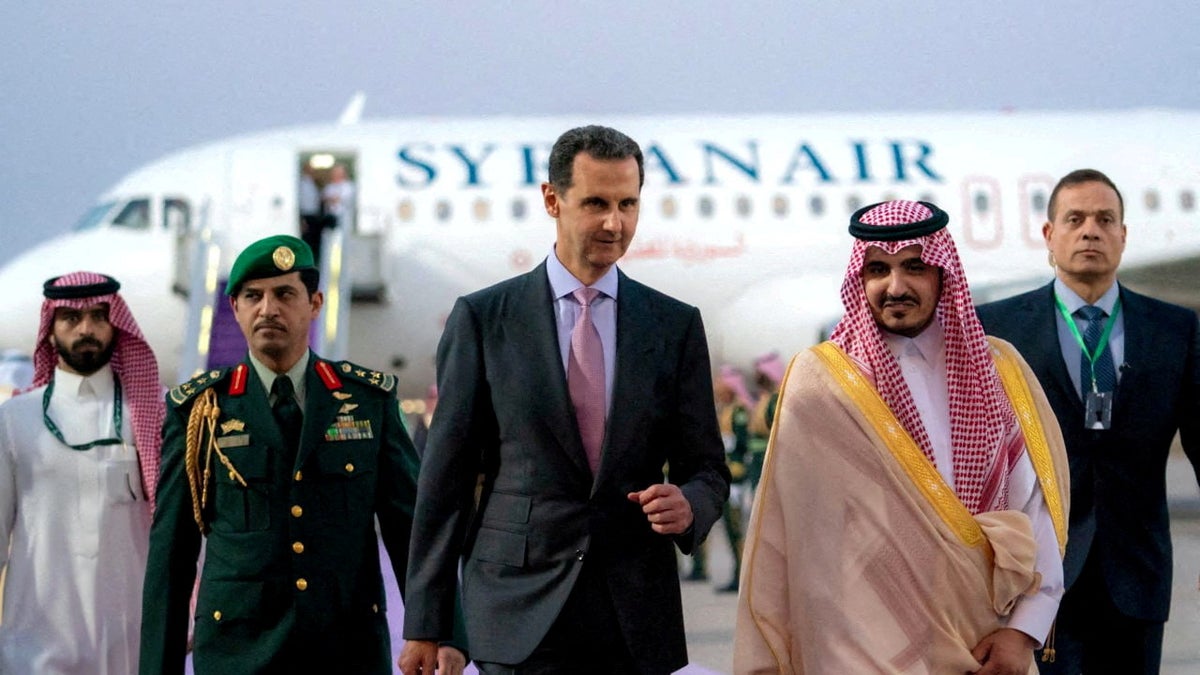 O presidente da Síria, Bashar al-Assad, caminhando em uma pista em Jeddah, Arábia Saudita, com um avião atrás dele