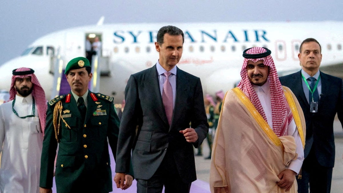 Syria's President Bashar al-Assad walking on a tarmac in Jeddah, Saudi Arabia with an airplane behind hime