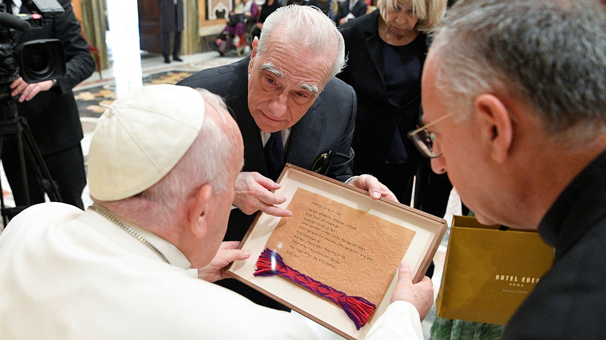 Pope Francis looks down at a frame that Martin Scorsese has presented him with