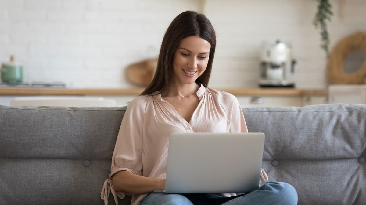 Woman smiles as she works on her laptop computer