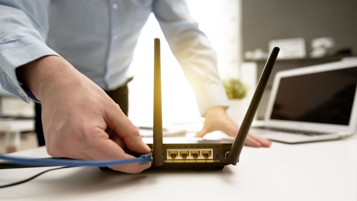 Man plugs wire into wifi router