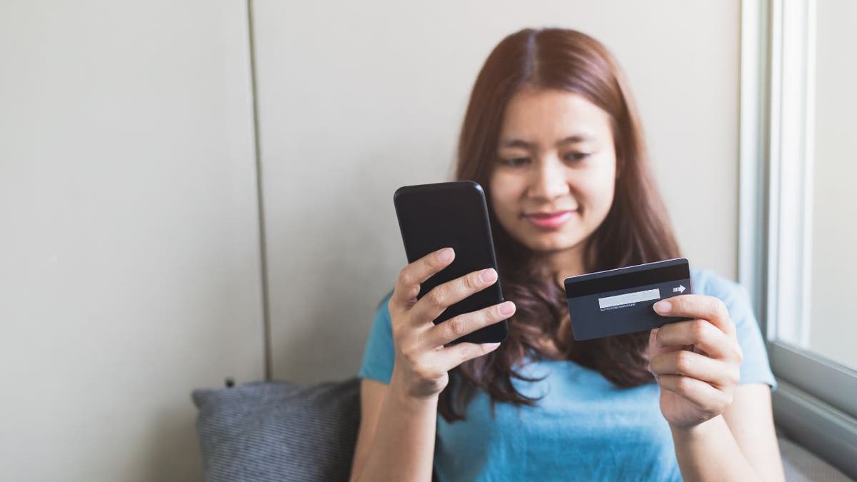 Woman entering her card information into her phone.