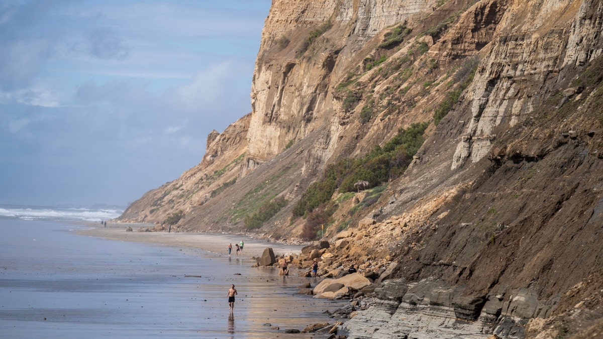 People move past a San Diego, California, bluff collapse