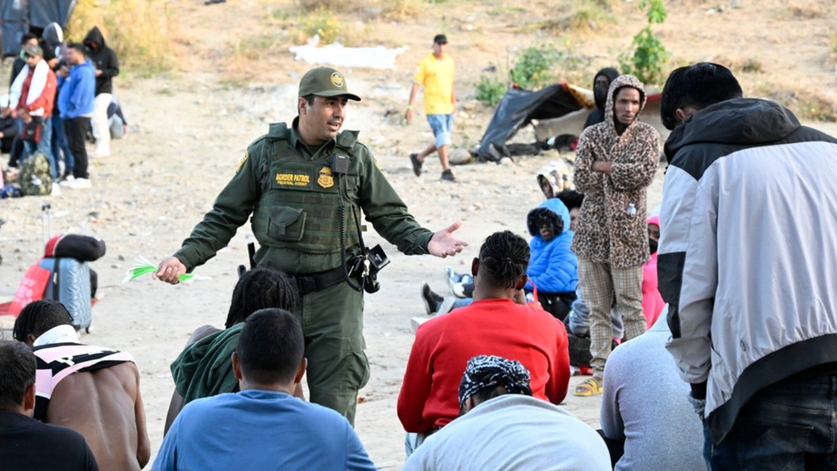 A U.S. Border Patrol agent talks with asylum-seekers