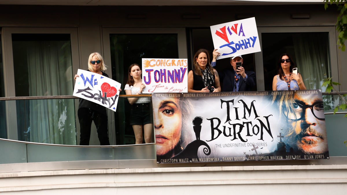 Fans hold signs in support of Johnny Depp at the Cannes Film Festival, with slogans saying "Viva Johnny" and "Congrats Johnny"