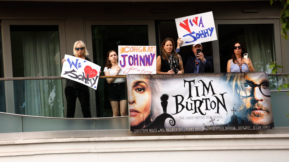 Fans hold signs in support of Johnny Depp at the Cannes Film Festival, with slogans saying "Viva Johnny" and "Congrats Johnny"