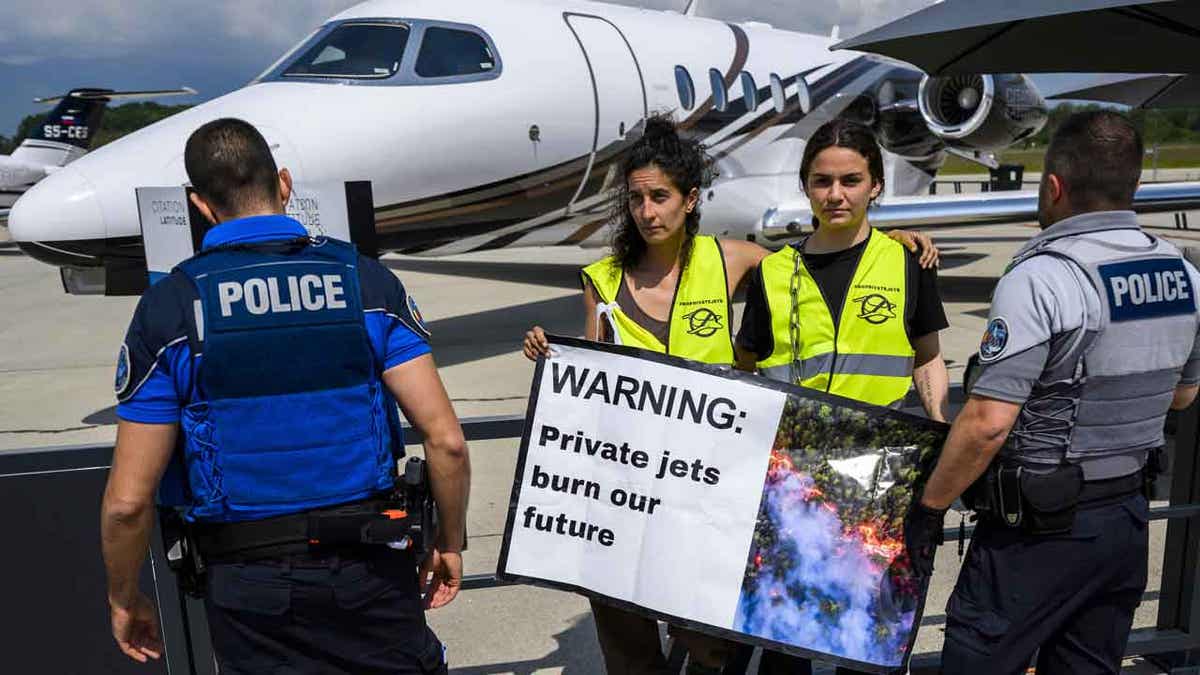 Environmental activists protest in front of an aircraft during the European Business Aviation Convention and Exhibition in Geneva, Switzerland, on May 23, 2023. 