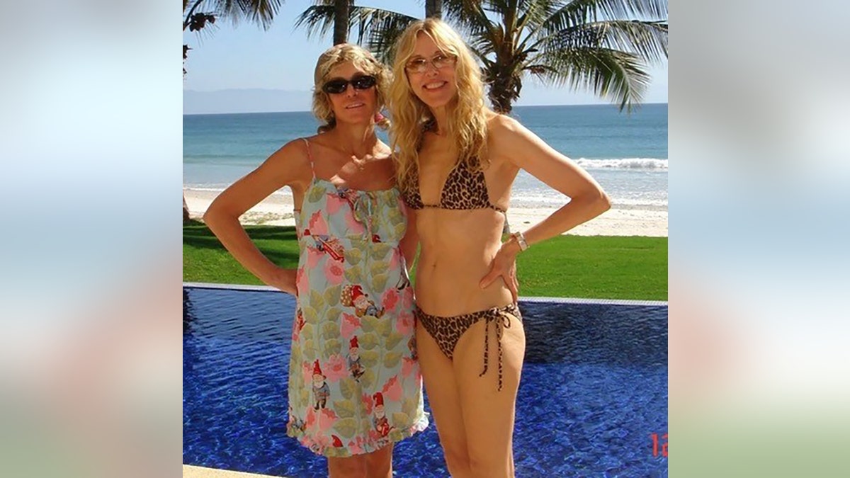 Farrah Fawcett wearing a green cover-up next to Alana Stewart in a bikini