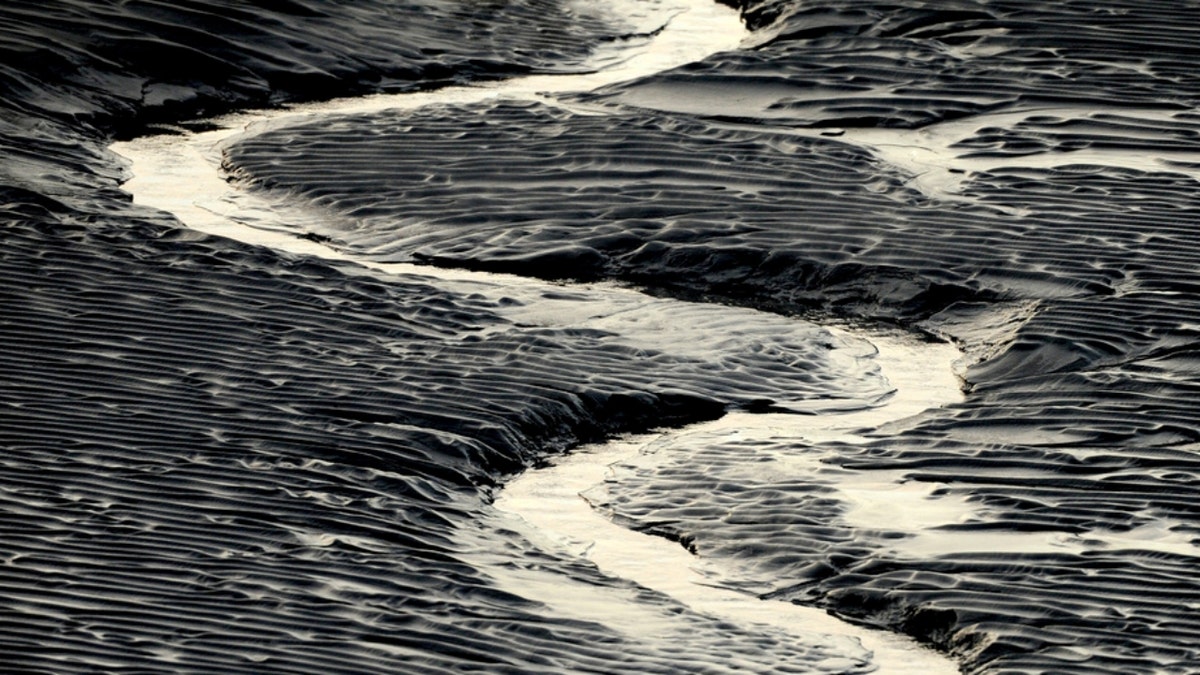 A channel flows through Alaska mud flats