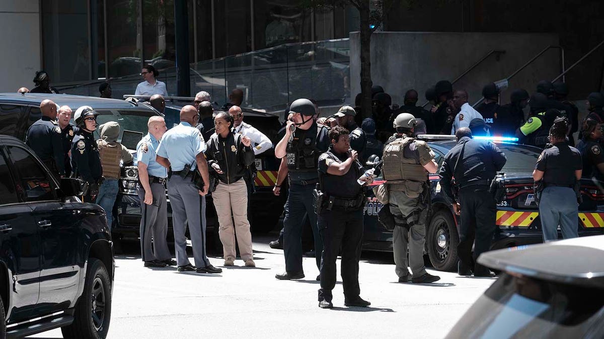 People stand outside a commercial building after a shooting, Wednesday, May 3, 2023, in Atlanta.