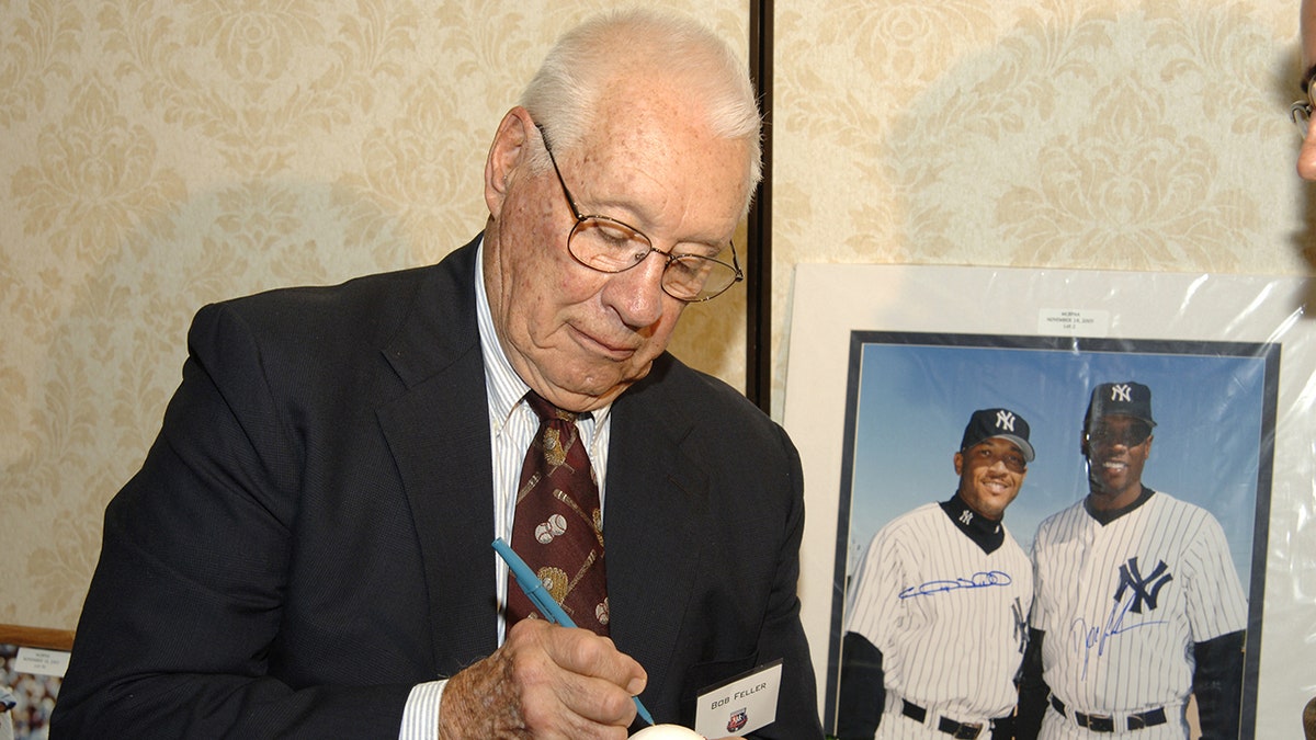Hall of Famer Bob Feller signs a baseball