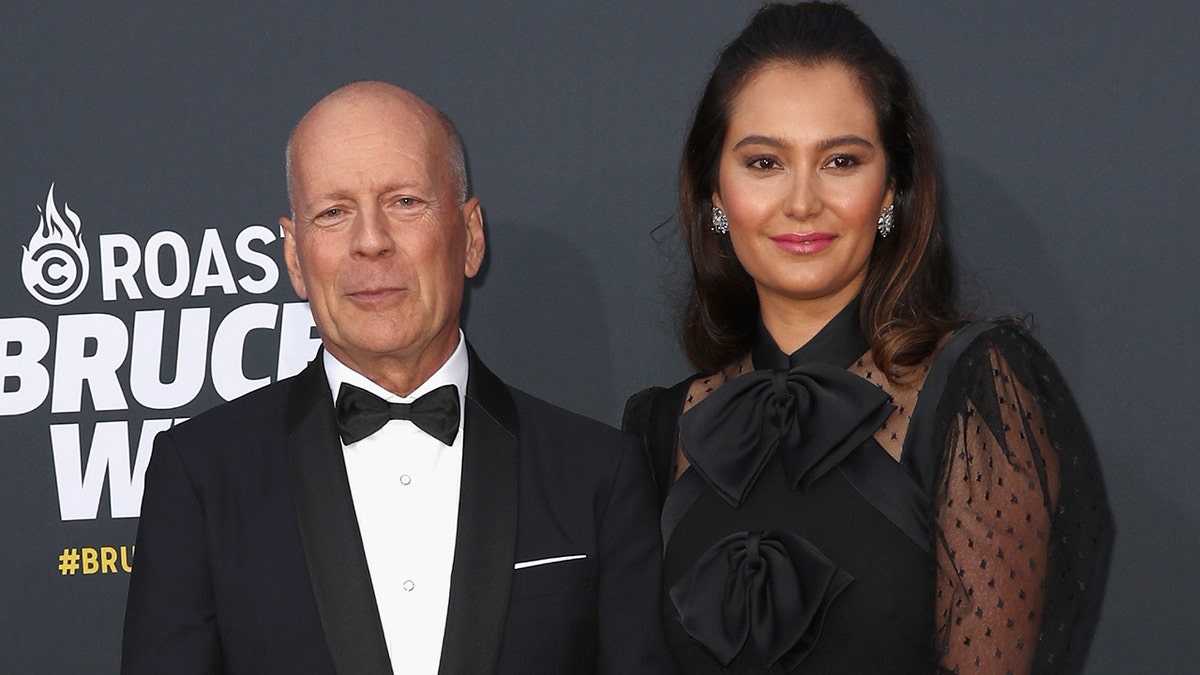 Bruce Willis soft smiles for a picture with Emma Heming Willis on the carpet in Los Angeles