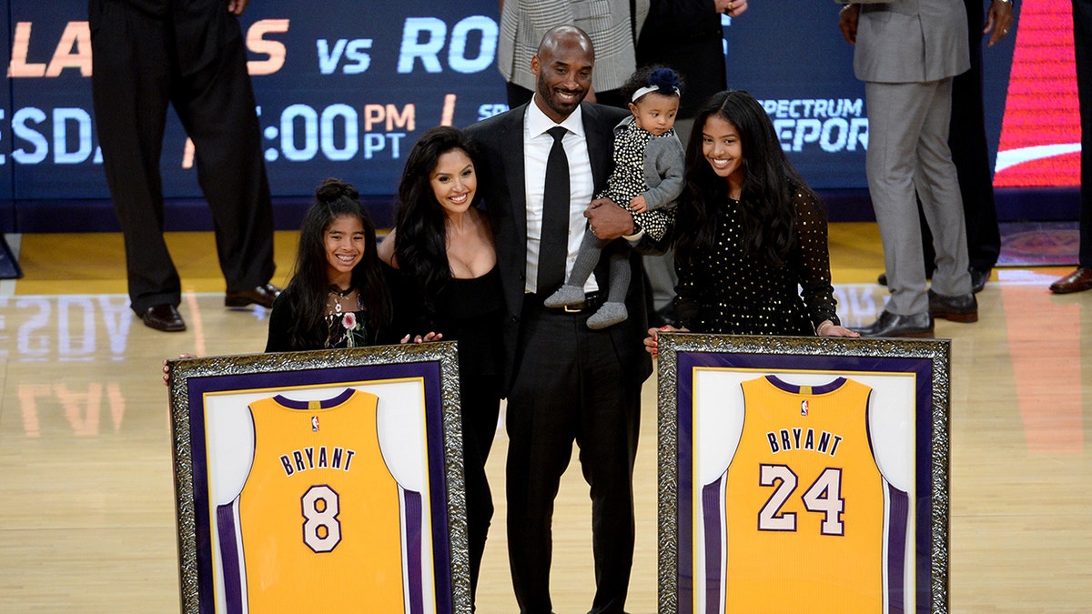 Kobe Bryant and his family pose by retired jerseys