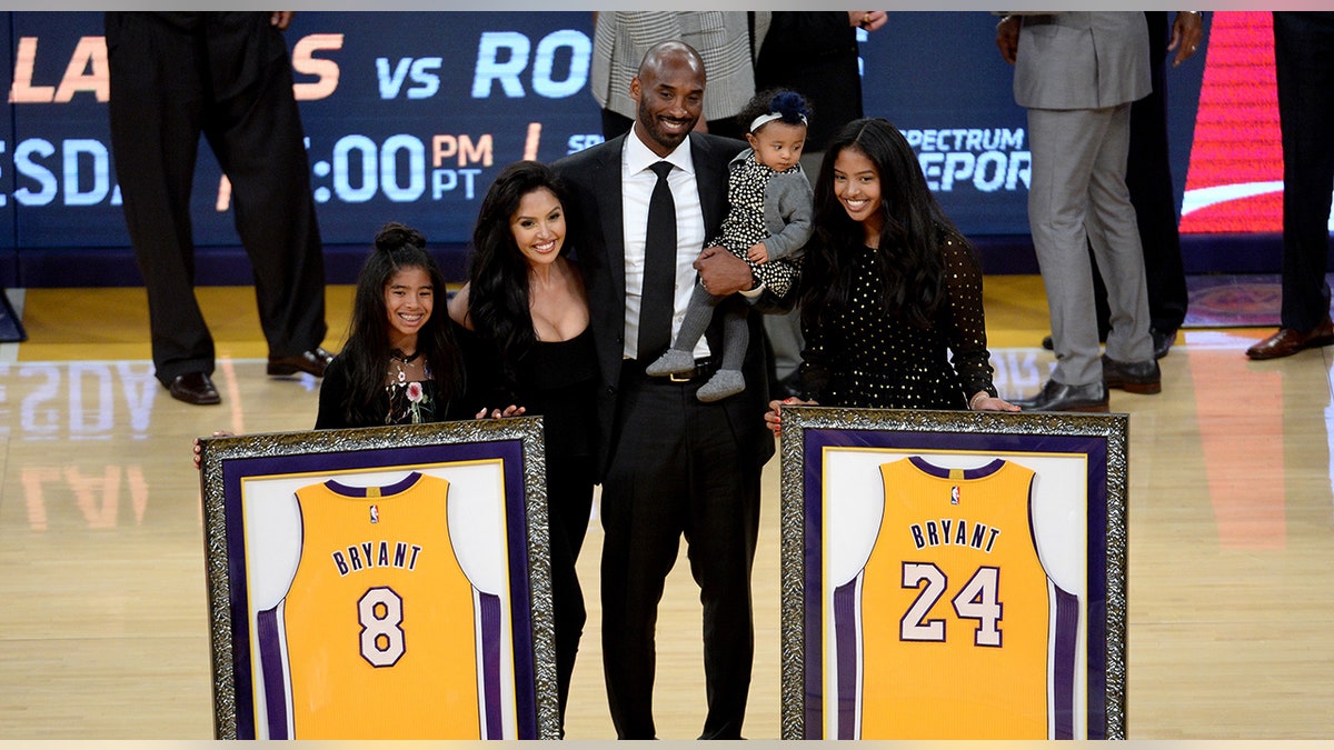 Kobe Bryant and his family pose by retired jerseys