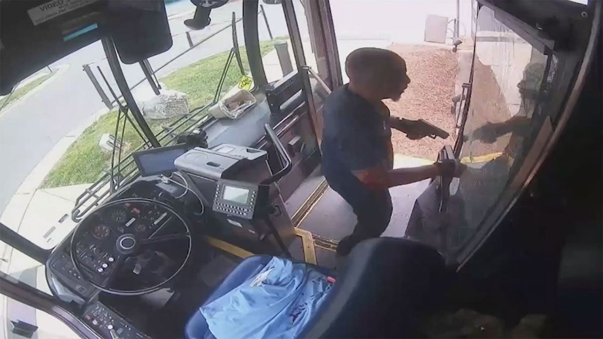 Bus driver standing at the front of the bus with his gun.