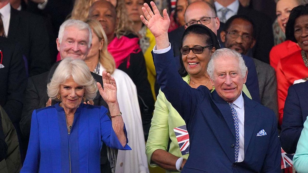 Britain's King Charles III (R) and Britain's Queen Camilla wave as they arrive to attend the Coronation Concert at Windsor Castle