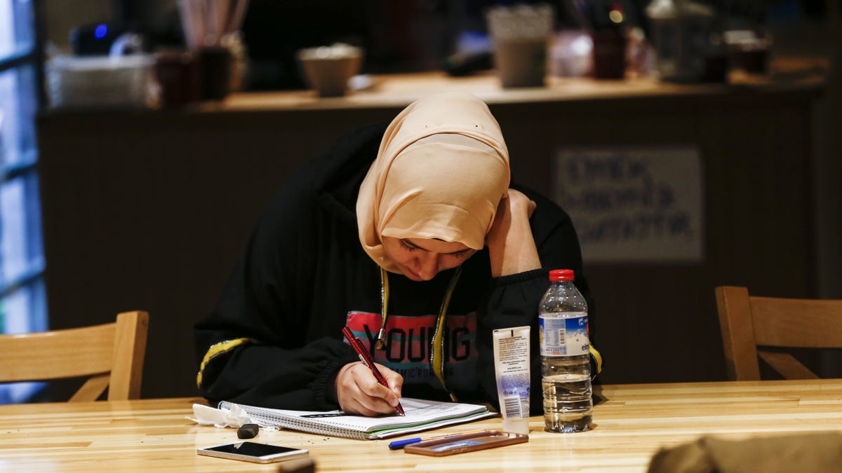 A student writes in a notebook at a table in a library-like cafeteria in Ankara, Turkey.