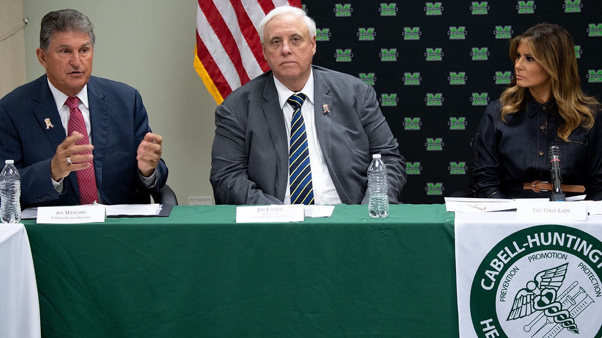 Jim Justice seen at a table between Melania Trump and Joe Manchin