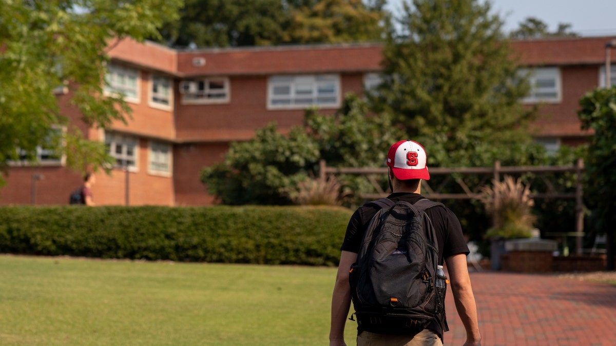 A student walks toward a dorm on the NCSU campus