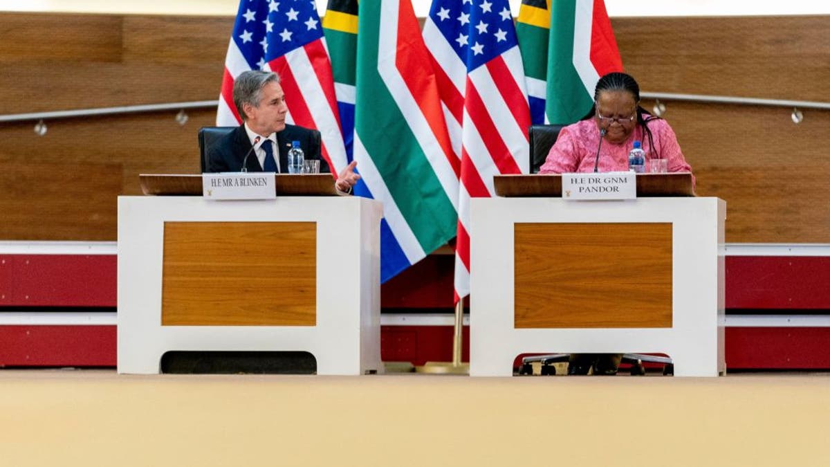 Blinken and Pandor at summit, US, South Africa flags behind them