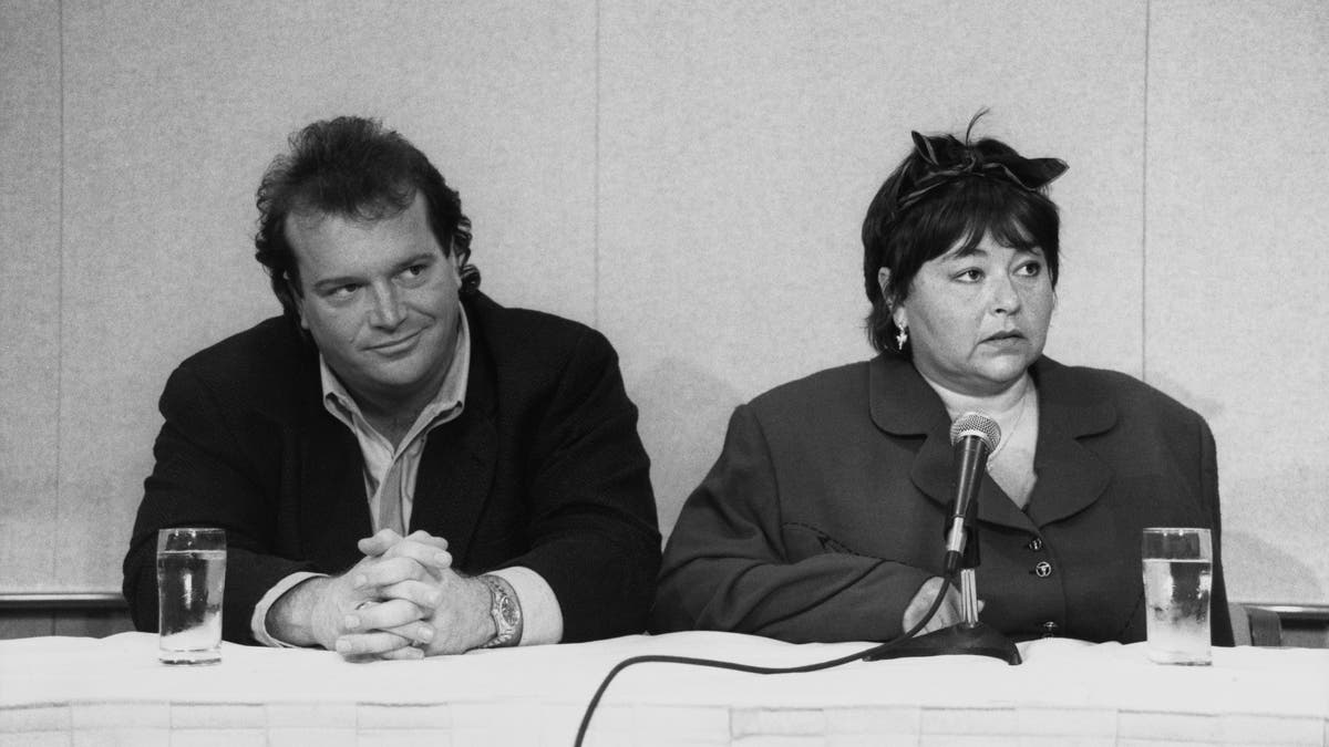 Black and white photo of Tom Arnold and Roseanne Barr at the press conference addressing her national anthem performance.