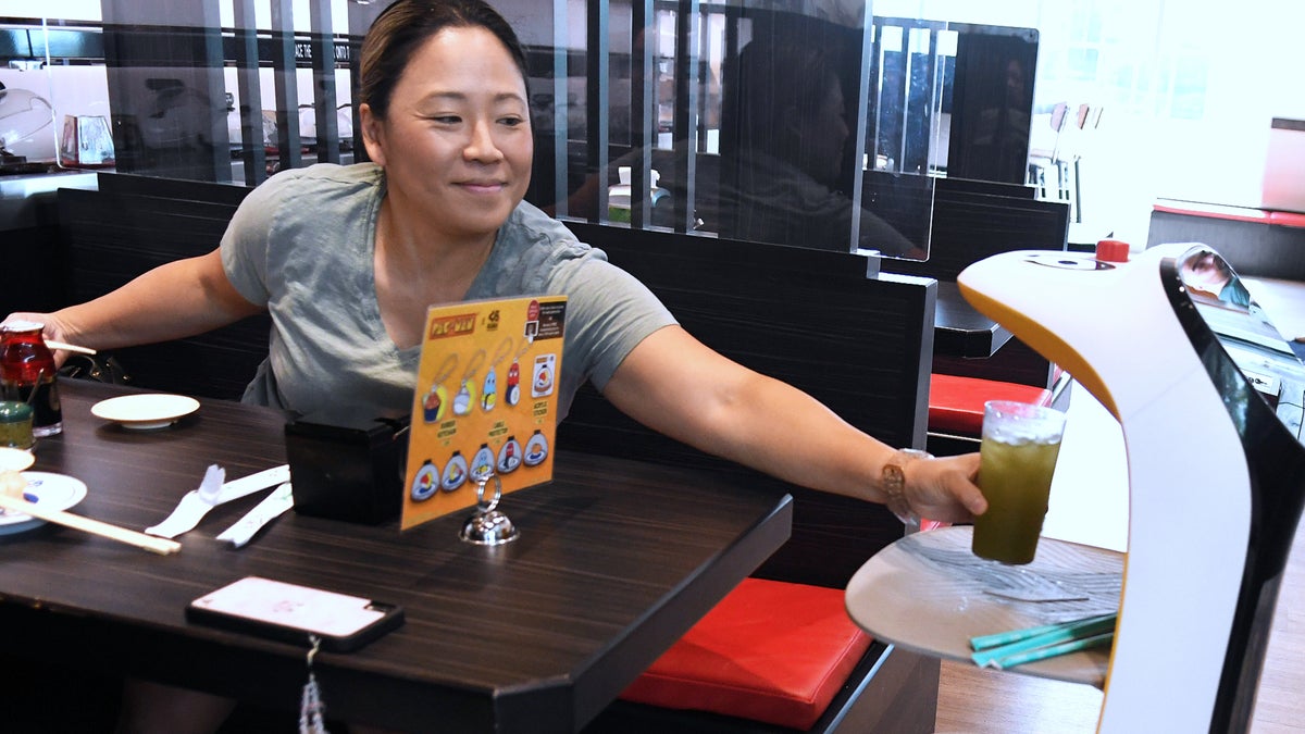 A robot waiter serves a woman at a restaurant in Orlando, Florida, in Sept. 2022.