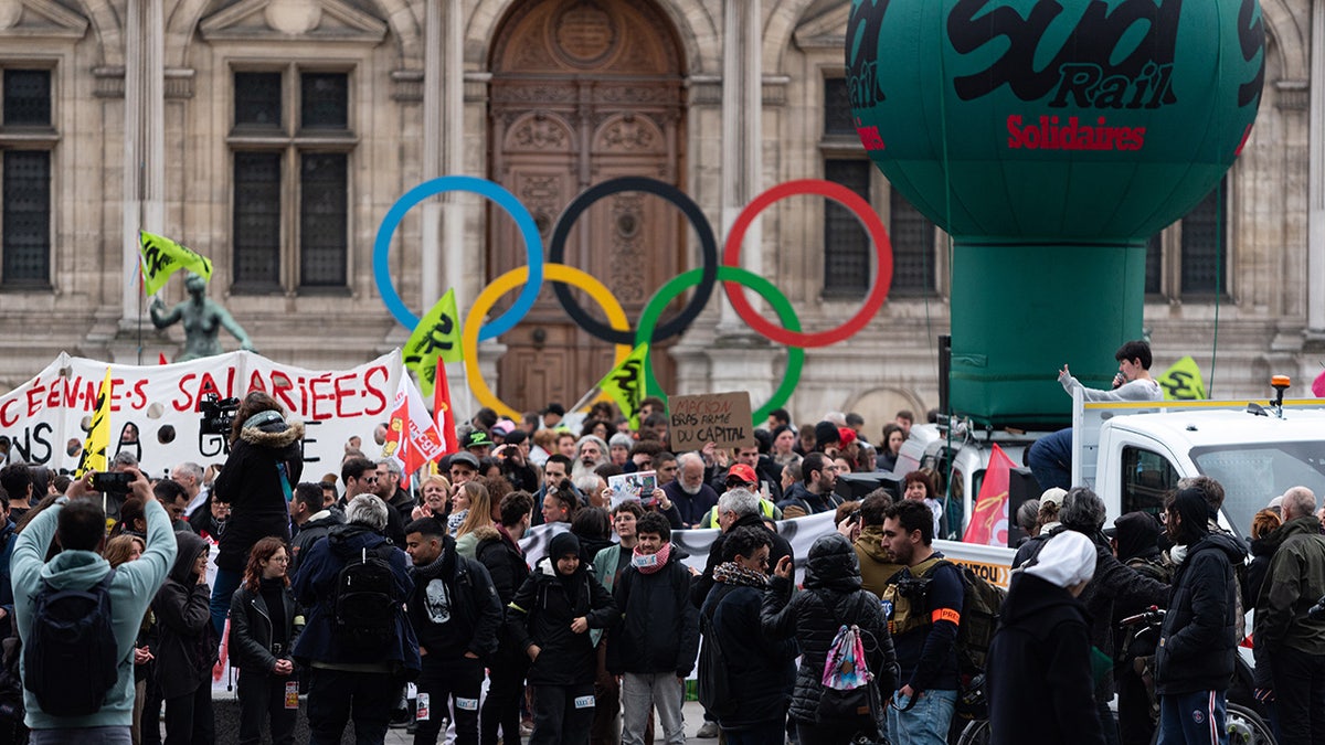 Paris protesters by Olympics sign