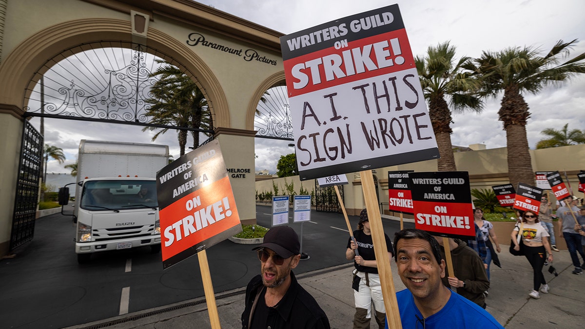 Writers on strike in Los Angeles carry signs that highlight what they take issue with, with one sign saying "A.I. THIS SIGN WROTE"