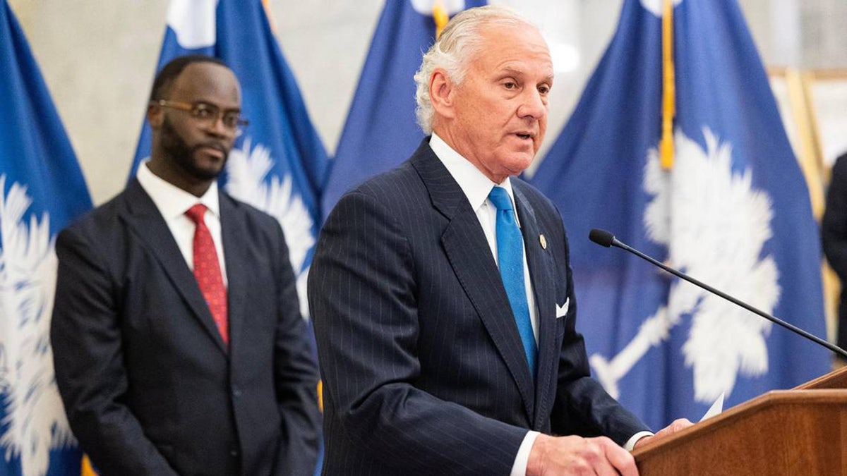 Gov. Henry McMaster speaks to reporters with South Carolina Comptroller General Brian Gaines standing behind him