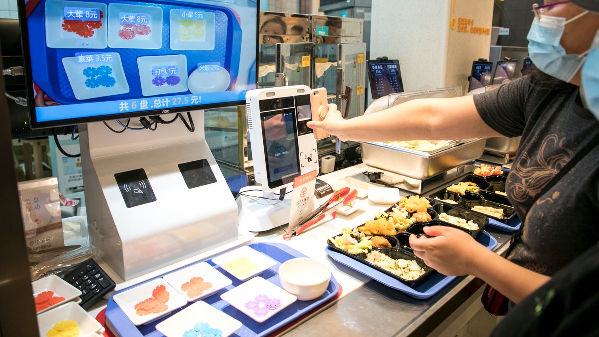 woman paying for food at cafeteria with smartphone