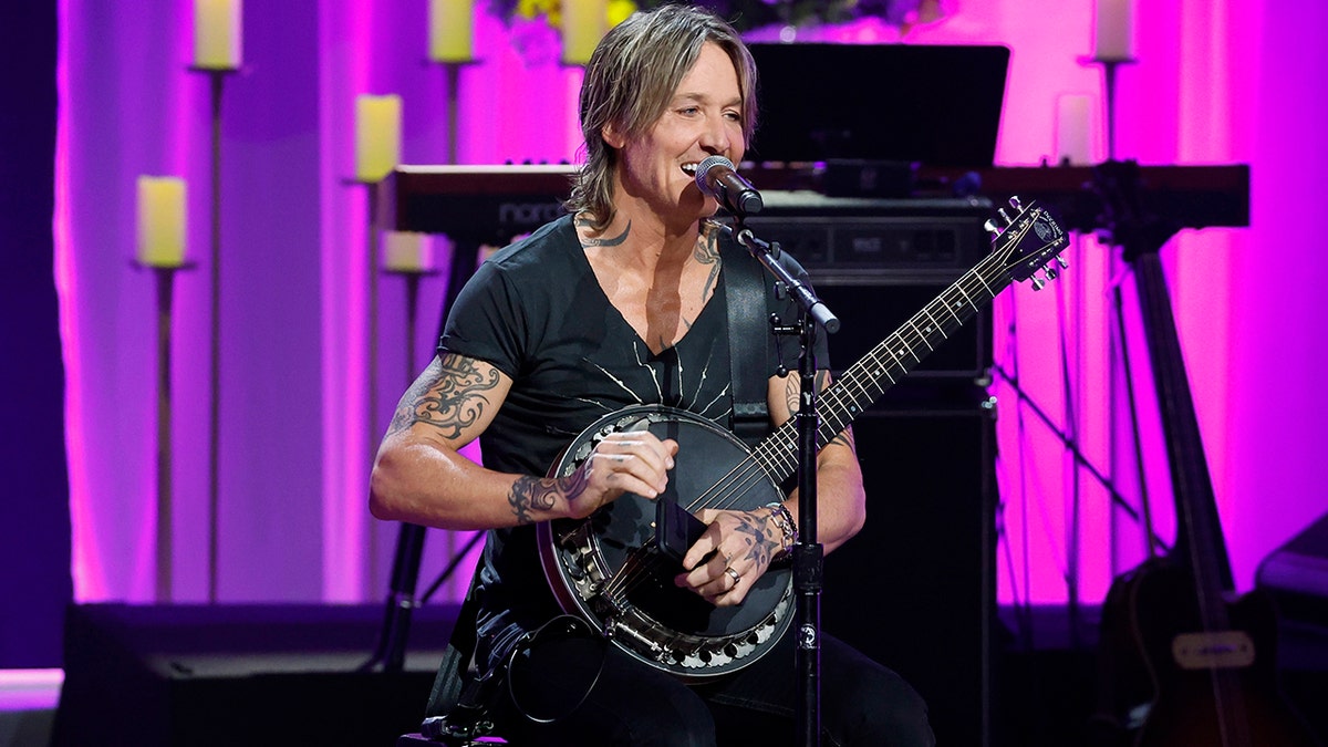 Keith Urban playing the banjo on stage