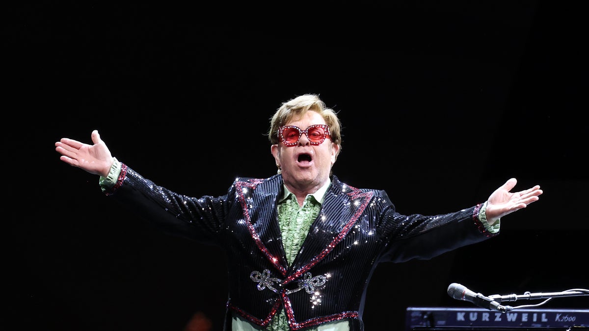 Elton John with his arms out to the crowd on stage