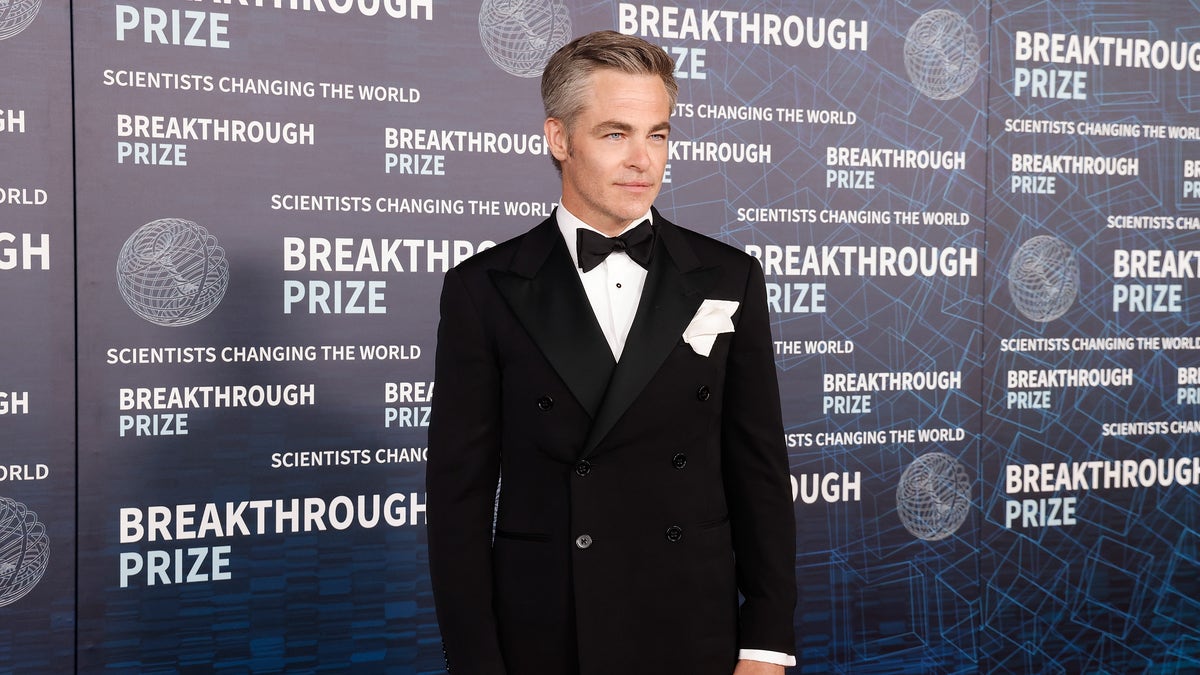 Chris Pine in a tuxedo on a red carpet.