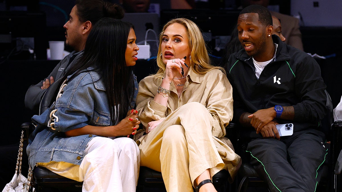 Nia Long faces Adele as they engage in conversation courtside at the Laker's game, while Rich Paul looks on