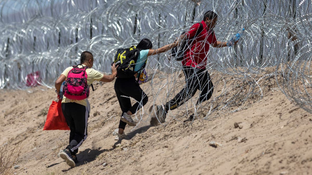 Migrants push through razor wire upon crossing from Mexico into El Paso on May 11, 2023.