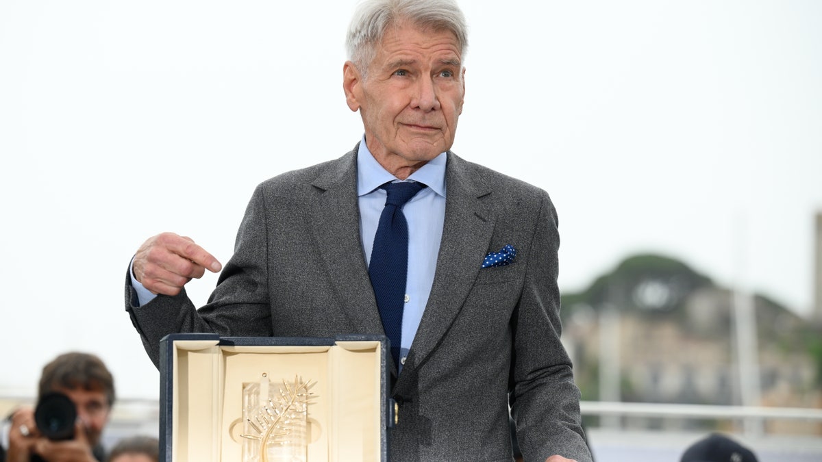 Harrison Ford pointing at his Palme D'Or award in Cannes