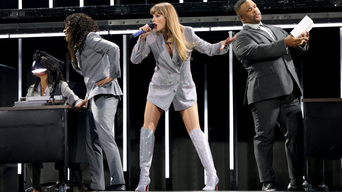 Taylor Swift performs on stage in sparkly blazer and boots