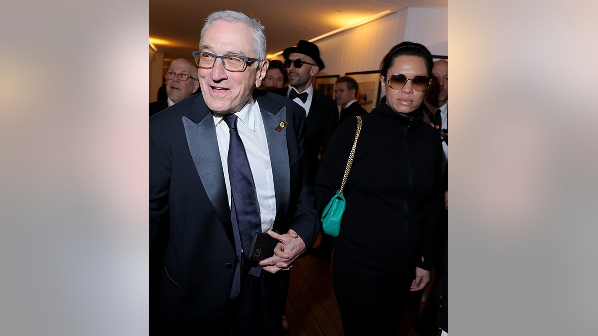 Robert De Niro smiles as he holds Tiffany Chen's hand and walks into the Vanity Fair x Prada party
