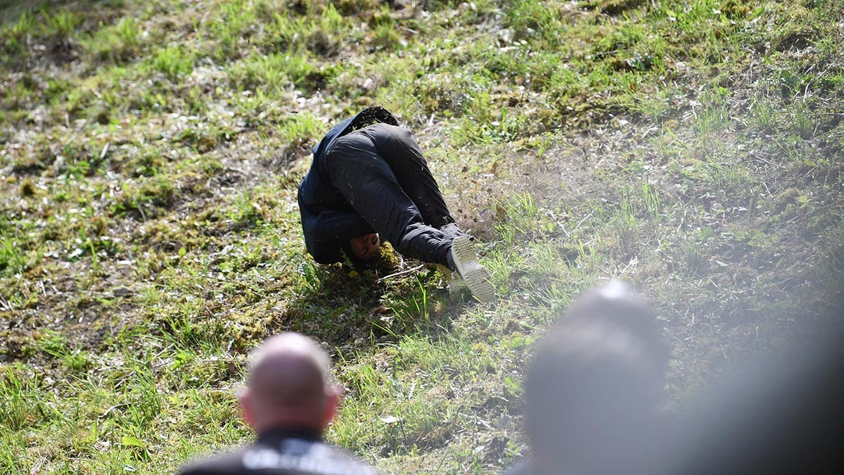 A woman falls down the hill at the annual cheese rolling race in England