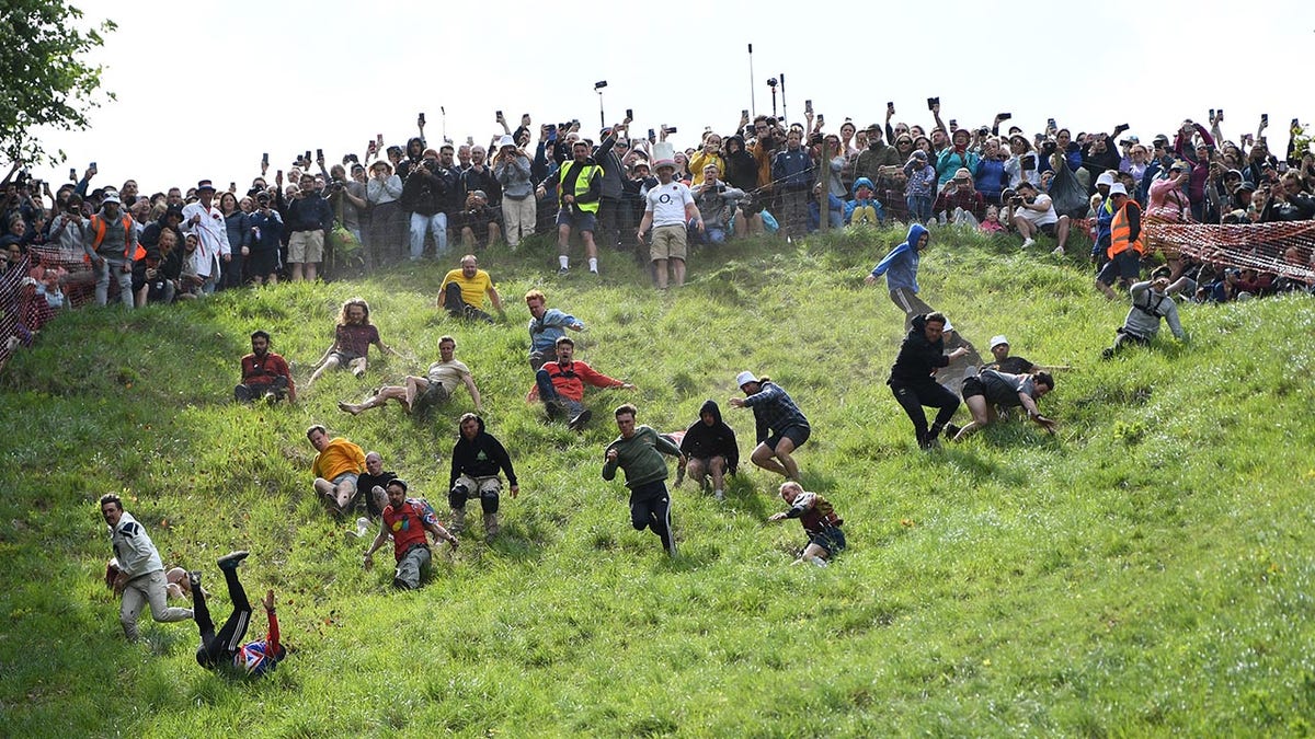Competitors chase after a cheese wheel during the annual cheese rolling race in the uk