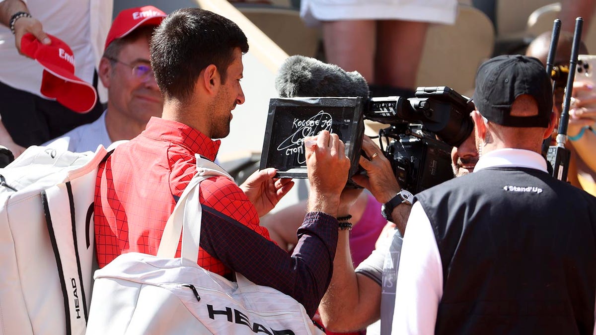 Novak Djokovic signs the camera after winning his first round match at the French Open