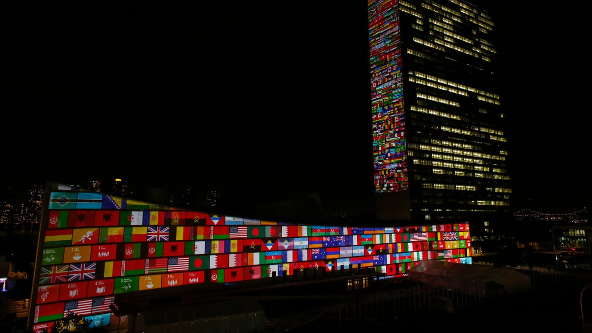 UN at night, right, with flags of member countries on display at left