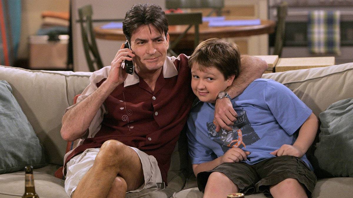 Charlie Sheen raps his arm around a young Angus T. Jones on the set of "Two and a Half Men"