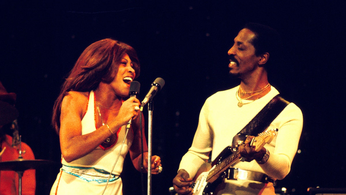 Tina Turner performs in a white dress alongside Ike Turner.