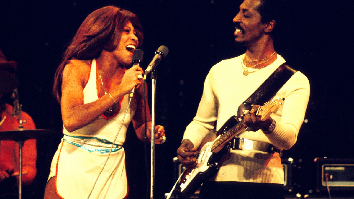 Tina Turner performs in a white dress alongside Ike Turner.
