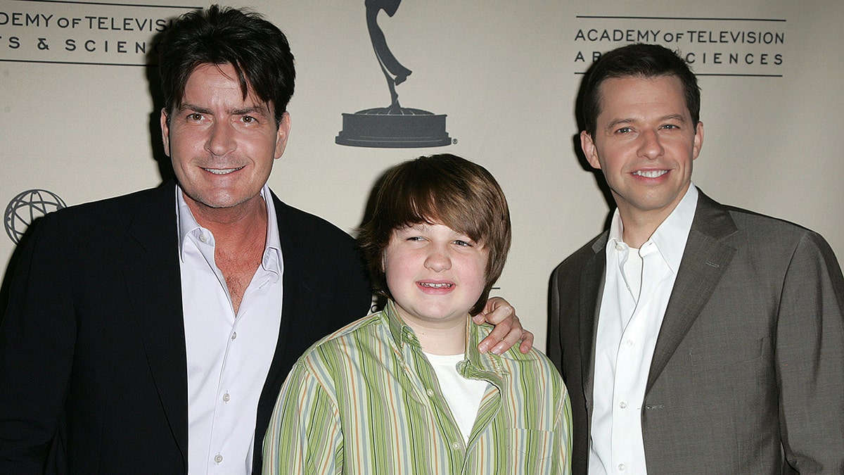Charlie Sheen holds on to Angus T. Jones next to Jon Cryer at an event for "Two and a Half Men"